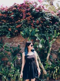 Young woman wearing sunglasses against plants