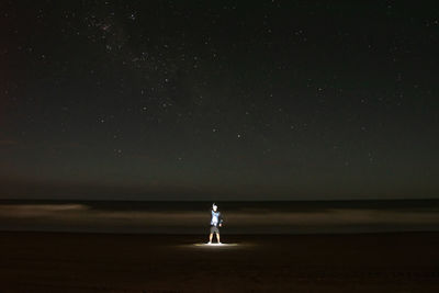 Night photograph of an illuminated man at the seashore, buenos aires with southern cross in the sky