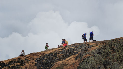 Low angle view of people on mountain against sky