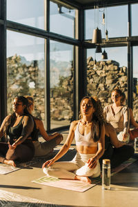 Women with eyes closed sitting back to back while exercising at retreat center