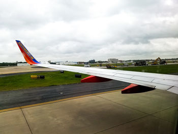 Airplane flying over airport runway against sky