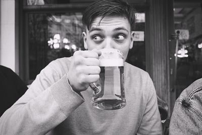 Portrait of young man drinking glass in restaurant