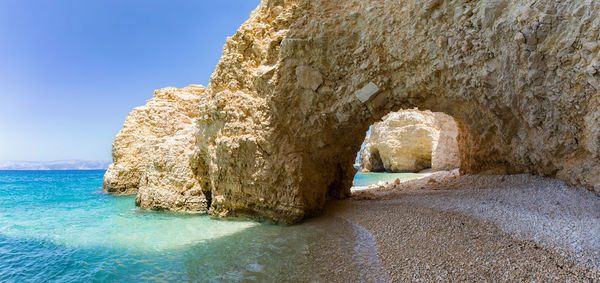 Rock formation in sea against clear sky