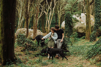 Millennial man and woman with dogs on a leash in the natural park