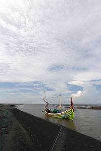 Fishing boats moored on sea against sky