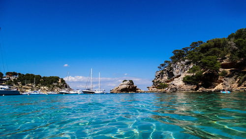 Sailboats in sea against clear blue sky