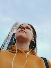 Low angle view of young woman against sky