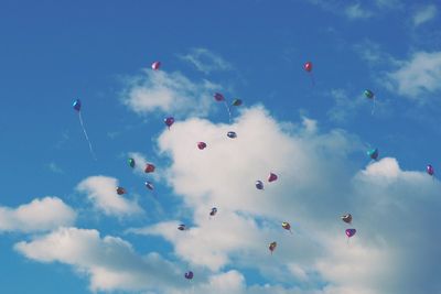 Low angle view of balloons flying against blue sky