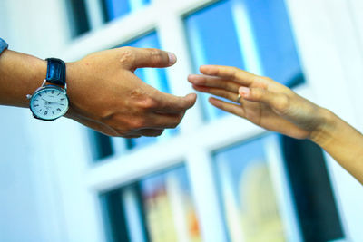 Close-up of hand holding clock against blurred background