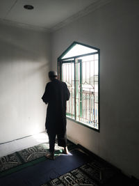 Rear view of man standing against wall at mosque