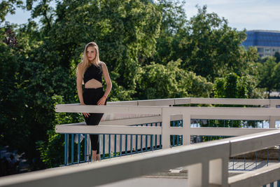 Thoughtful young woman standing on balcony against trees