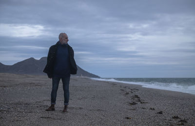 Adult man in winter clothes on beach during sunset. almeria, spain