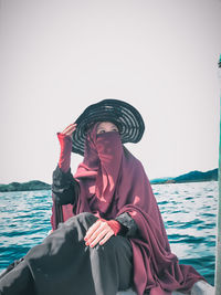 Woman wearing hat against sea against clear sky