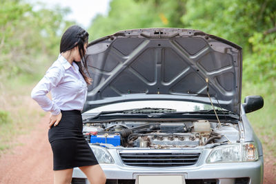 Businesswoman looking at car engine