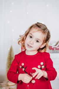 Portrait of cute little girl at home wearing red christmas dress at home over christmas decoration