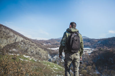 Rear view of man walking on mountain against sky