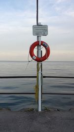 Close-up of stop sign on sea against sky