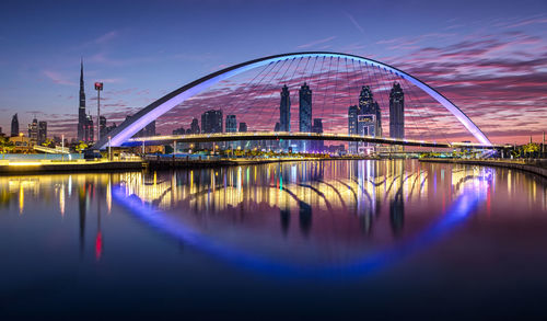 Modern bridge over river in city at dusk