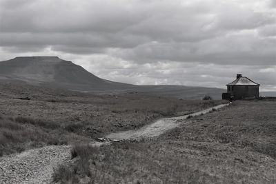 Scenic view of road by field against sky