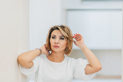 A beautiful woman in a white t-shirt preens for a date, straightens her hair, hair. mock-up. closeup