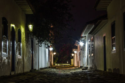 Empty narrow street along buildings at night