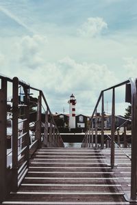 Empty pier amidst buildings against sky