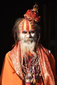 Portrait of a saddhu priest against black background