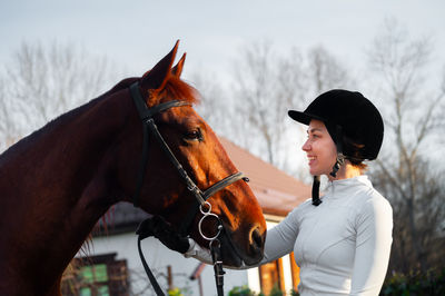 Side view of woman with horse standing against sky