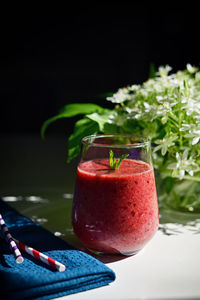 Tasty fresh berry smoothie, paper straws and star of bethlehem flowers in vase