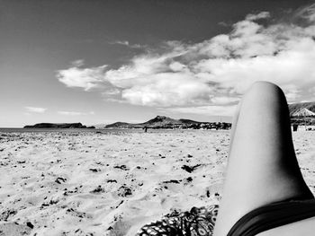 Midsection of woman lying on sand at beach against sky