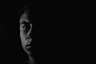 Close-up portrait of young man against black background