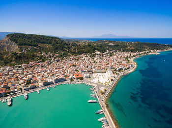 High angle view of townscape by sea against blue sky