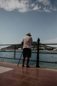 Rear view of man looking at sea against sky