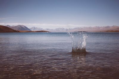 Water splashing in lake against sky