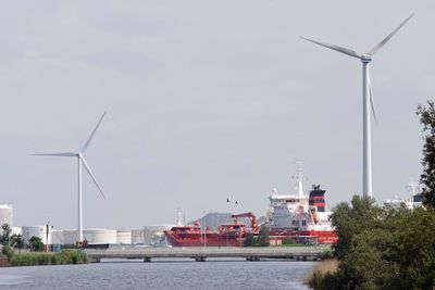 Wind turbines at harbor against clear sky