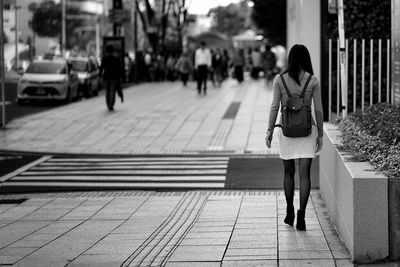 Rear view of woman walking on sidewalk