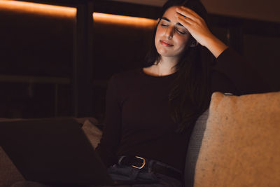 Young woman sitting on sofa at home