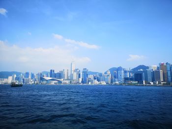 Sea by buildings against blue sky