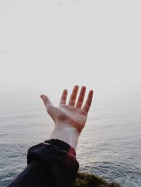 Close-up of human hand against the sea