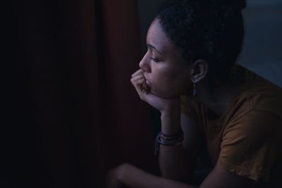 Pensive young woman sitting at home