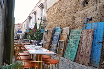 Empty chairs and tables in cafe amidst buildings in city