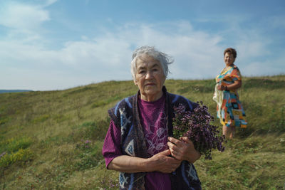 Grandmother with her daughter standing on field against sky