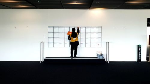 Rear view of woman standing against wall