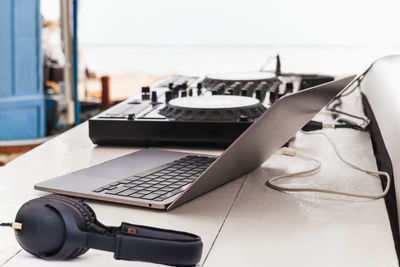 Dj sound control table mixing with headphone and laptop computer on table outdoors