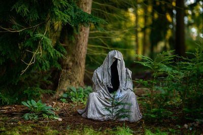 Halloween decoration ghost figure is sitting in the forest