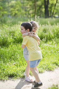 Happy girl hugging brother in park on sunny day