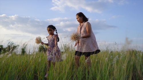 Woman with daughter holding flowers on land