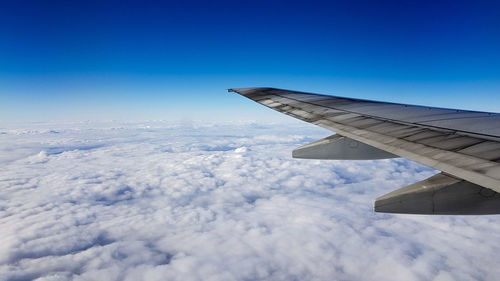 Airplane wing over clouds against blue sky