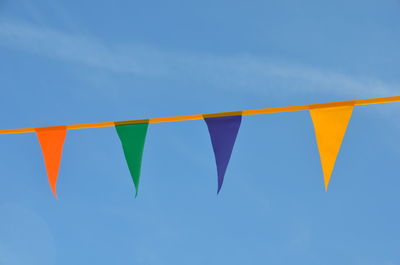 Low angle view of flags hanging against blue sky