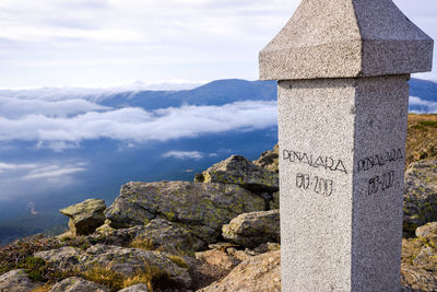 Stone cross on mountain against sky